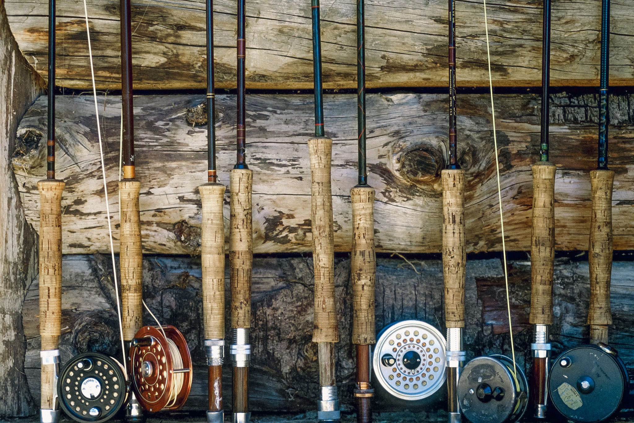 A row of fly fishing poles up along a wall.